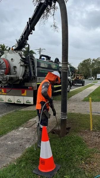Worker Using a Tool at a Drain Opening. a Truck With a Large Hose is Nearby — Tyzac Group in Beerwah, QLD