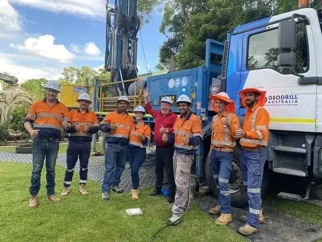 Group of Workers in Safety Vests and Hard Hats Pose With Drilling Truck — Tyzac Group in Beerwah, QLD