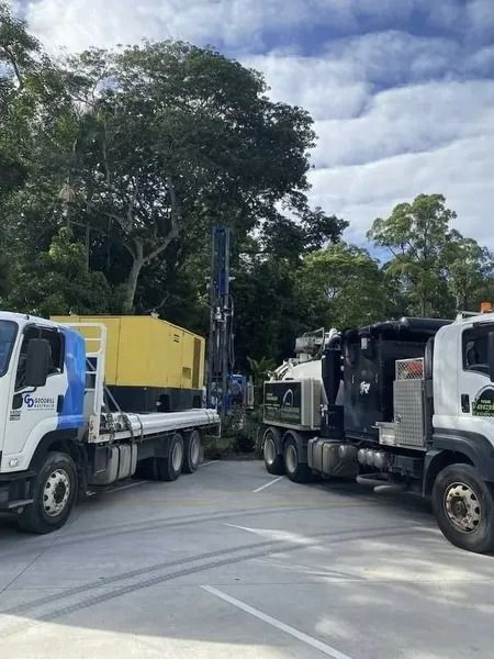 Trucks and Drilling Rig in a Parking Area, Trees in the Background, Cloudy Sky — Tyzac Group in Beerwah, QLD