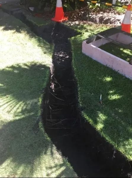 Long, Dark Trench Dug in Grass, Marked by Orange Cones, Near a Concrete Border — Tyzac Group in Beerwah, QLD