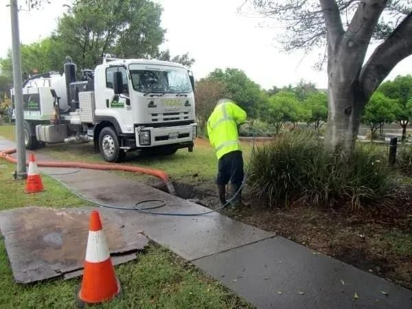 A Worker in a Yellow Vest Sprays a Sewer Line — Tyzac Group in Beerwah, QLD