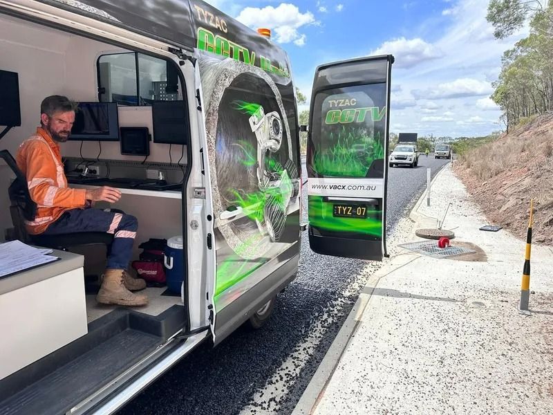 Man in Orange Vest in a Van, Working on a Computer Next to a Freshly Paved Road — Tyzac Group in Beerwah, QLD