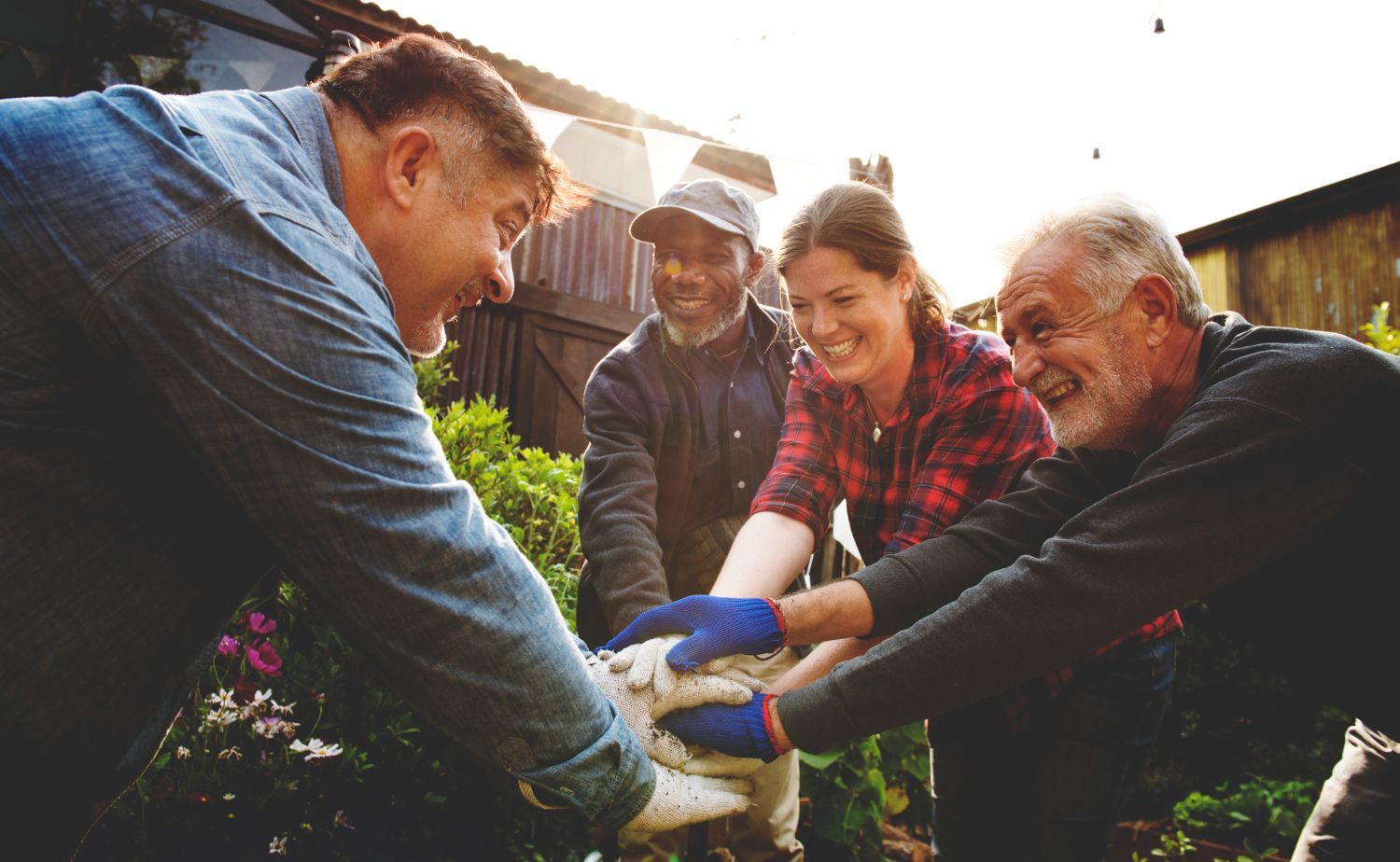 Group of people in a garden with hands together, smiling.