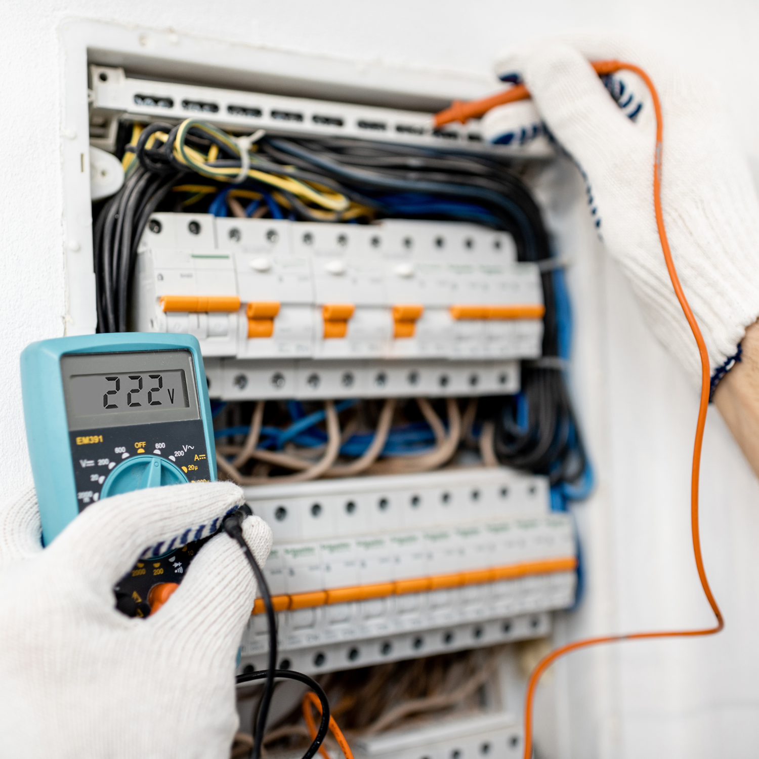 Electrician using a multimeter on a circuit breaker panel; reading 222V.