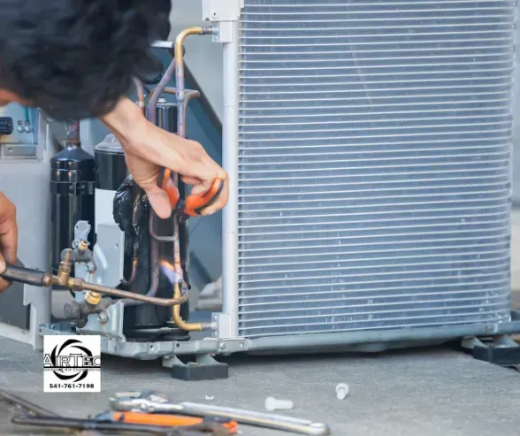 A man is working on an air conditioner with a screwdriver.