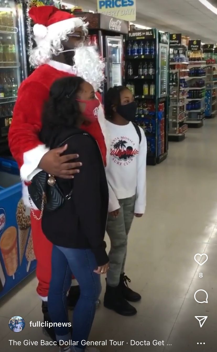 A man dressed as santa claus hugs a woman and child in a store