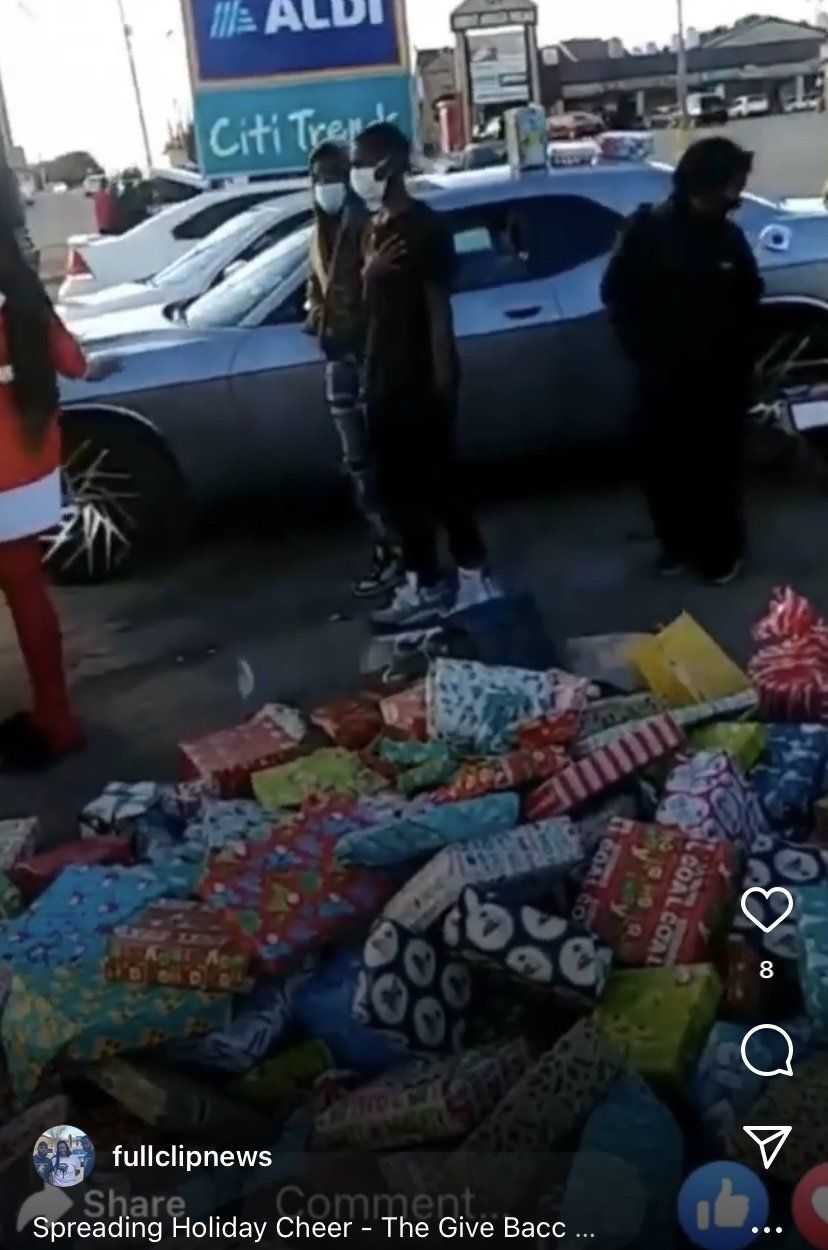 A group of people standing around a pile of wrapped gifts