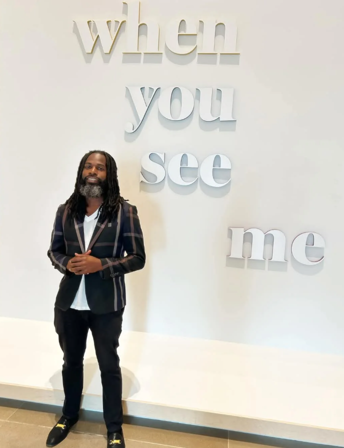 Man stands in front of wall art that reads 