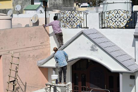 Two men are painting the side of a building.