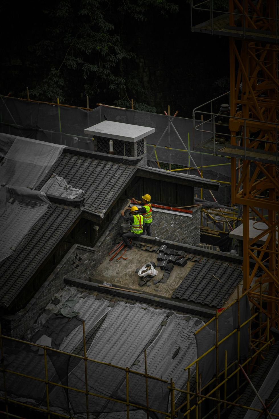 A couple of construction workers are standing on top of a building.