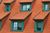 A row of houses with red tile roofs and green windows.