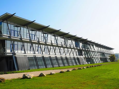 A large building with a lot of windows is surrounded by grass and rocks.