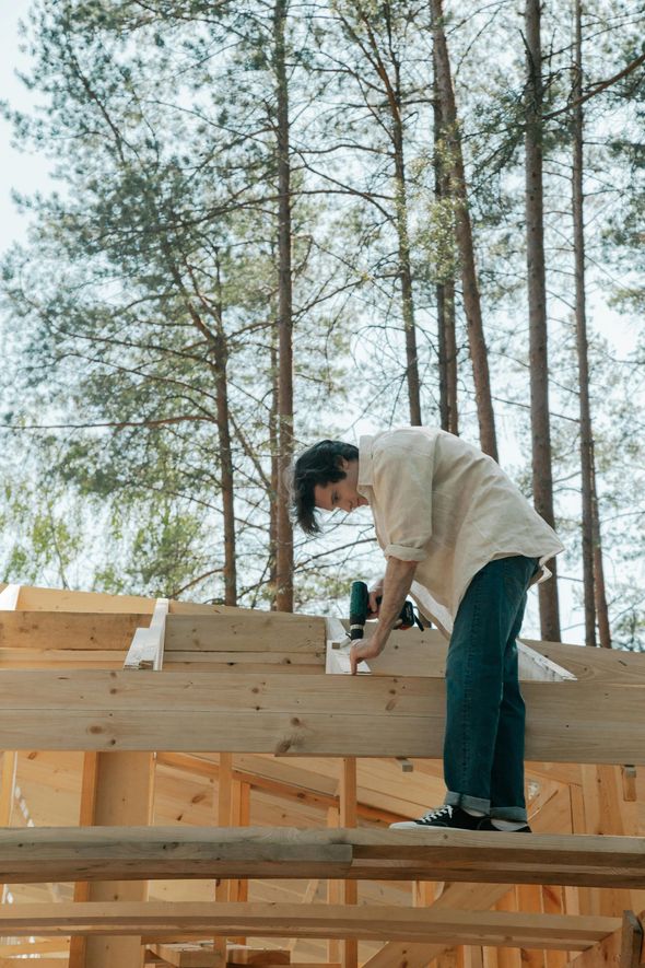 A man is working on a wooden structure in the woods.