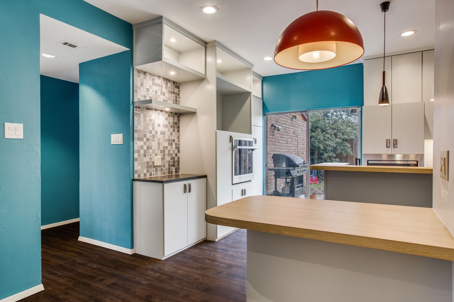 A kitchen with blue walls , white cabinets and a wooden counter top.