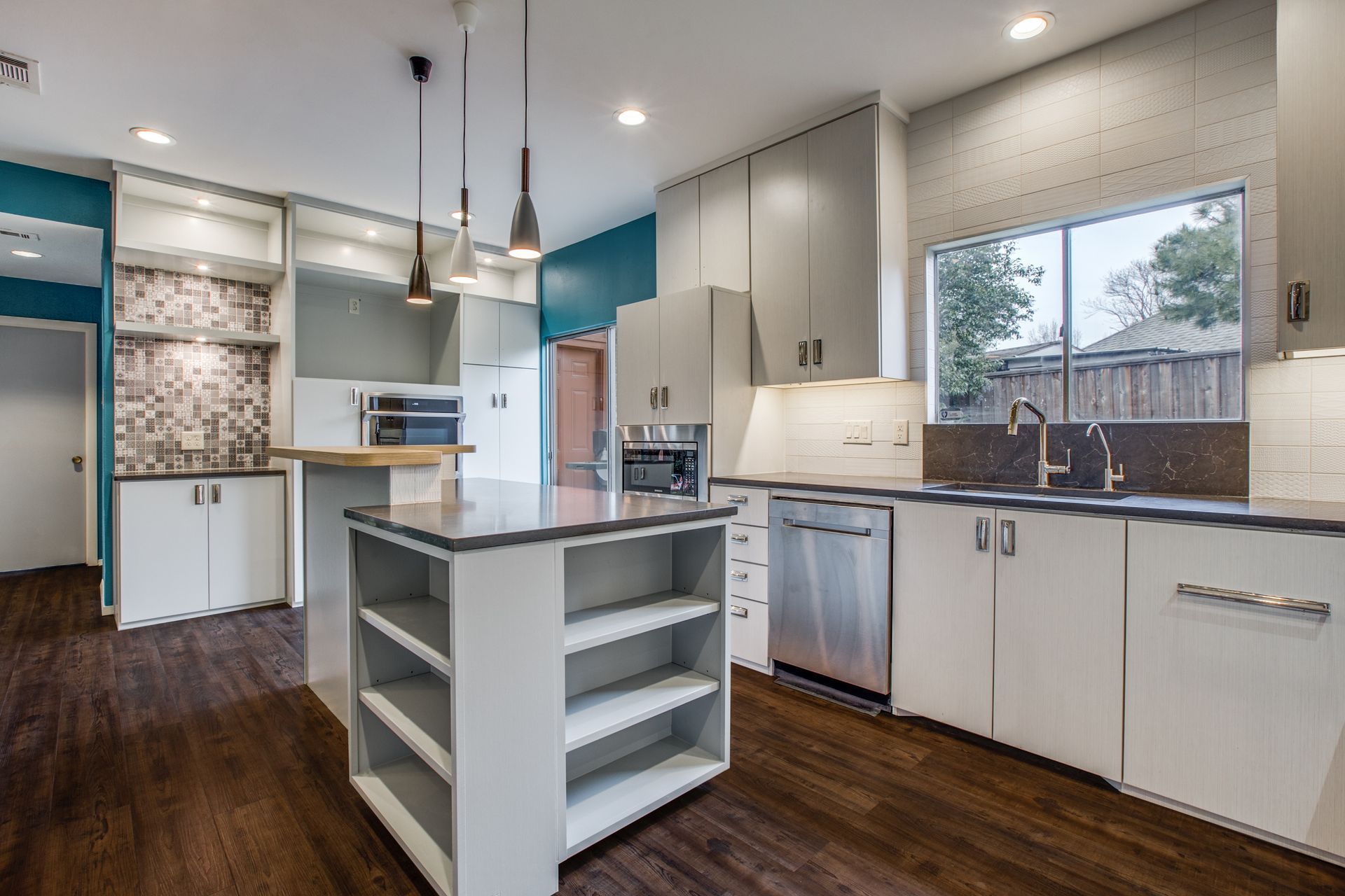 A kitchen with white cabinets and stainless steel appliances and a large island in the middle.