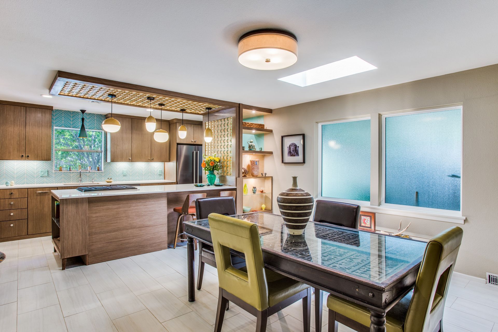 A dining room with a table and chairs and a kitchen in the background.