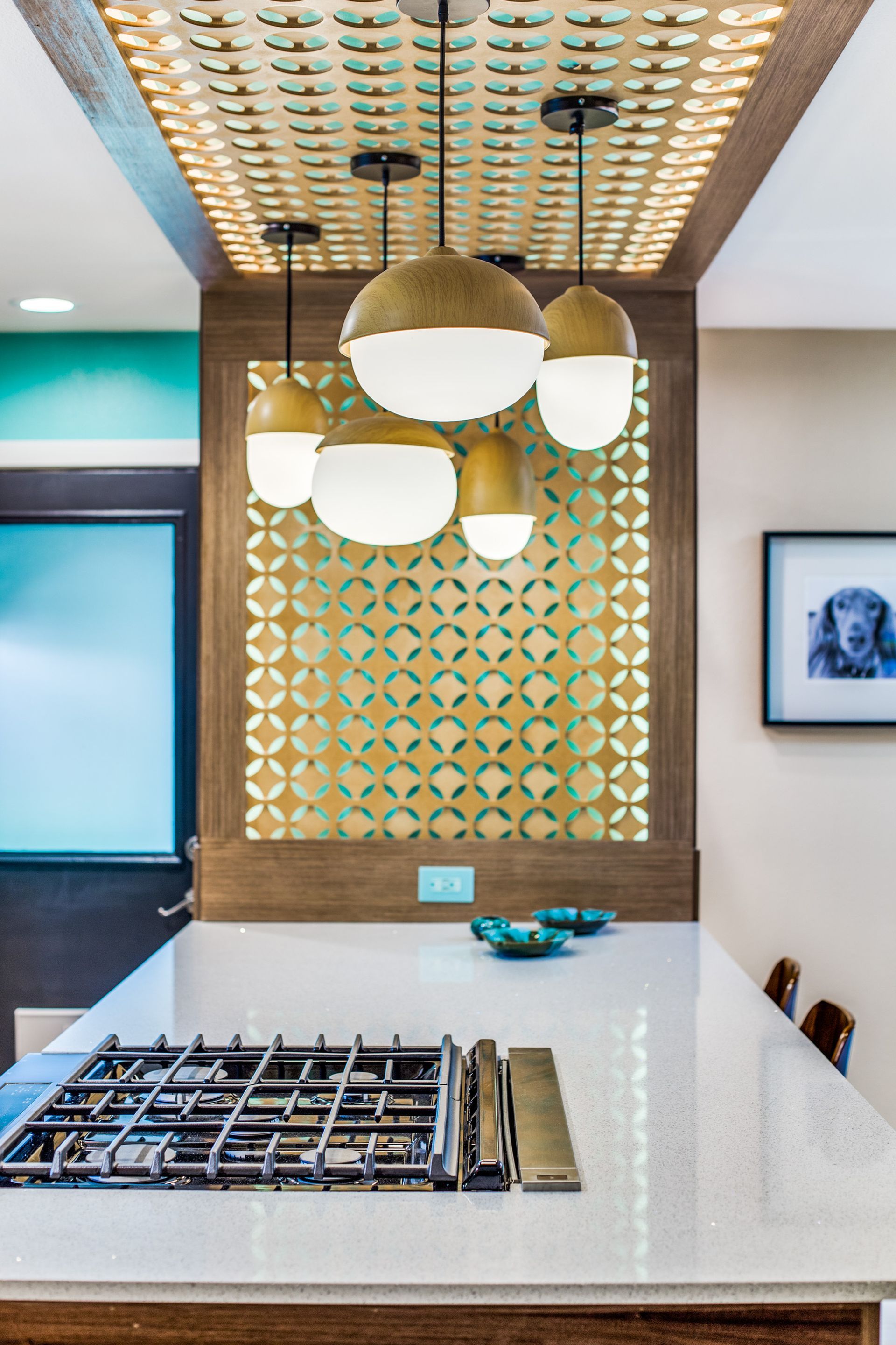 A kitchen with a stove top oven and pendant lights hanging from the ceiling.