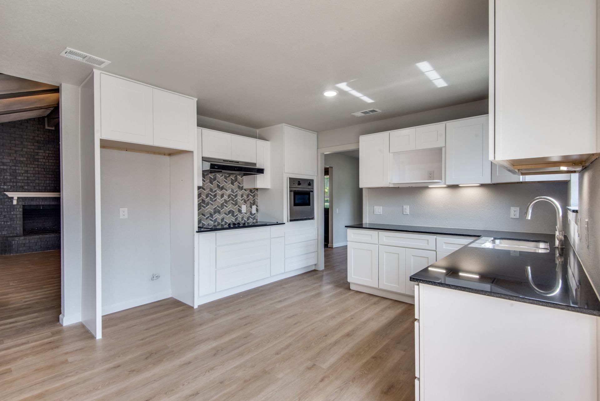An empty kitchen with white cabinets and a black counter top.