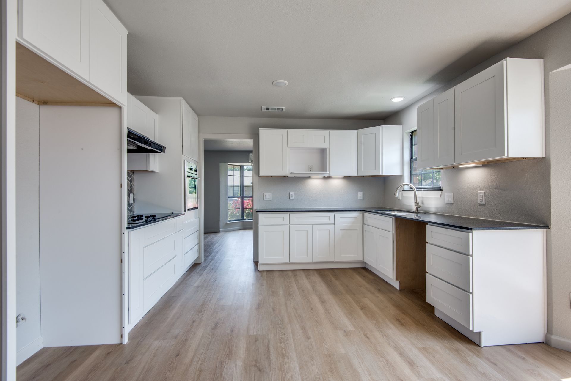 A kitchen with white cabinets and wooden floors