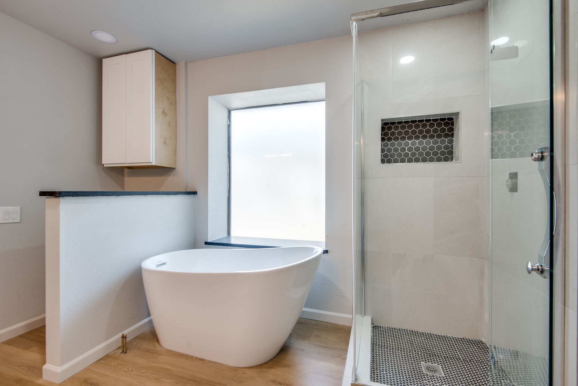 A bathroom with a tub , shower and window.