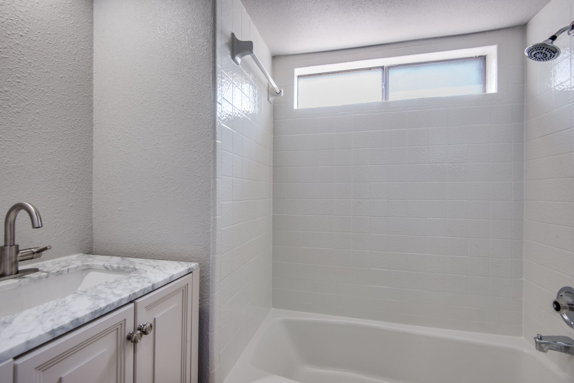 A bathroom with a sink , tub , shower and window.