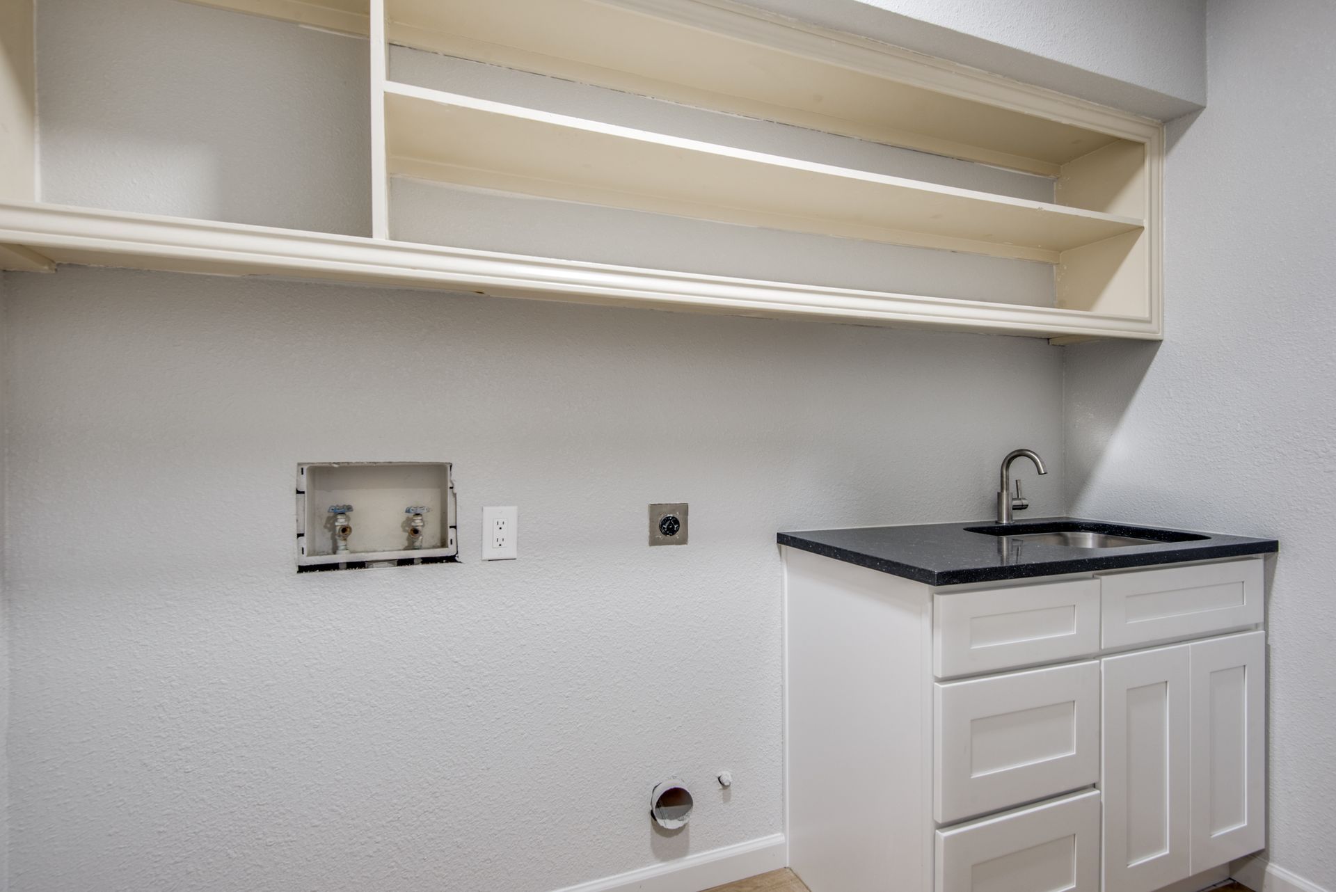 A laundry room remodel with white cabinets and a sink.