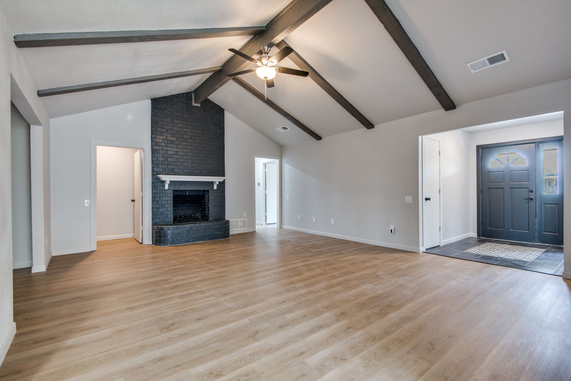 An empty living room with hardwood floors and a fireplace.