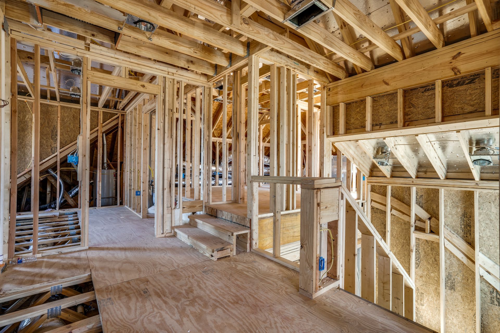 The inside of a house under construction with wooden beams and stairs.