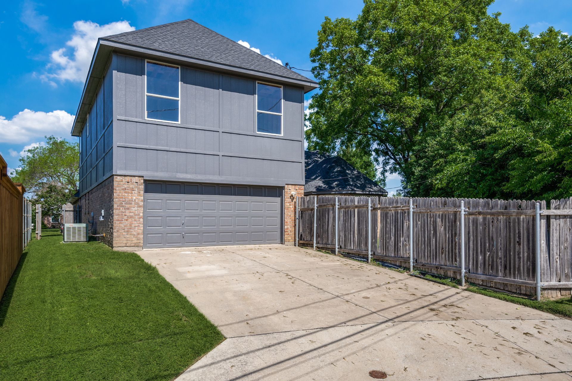A house remodel with a garage and a fence in front of it
