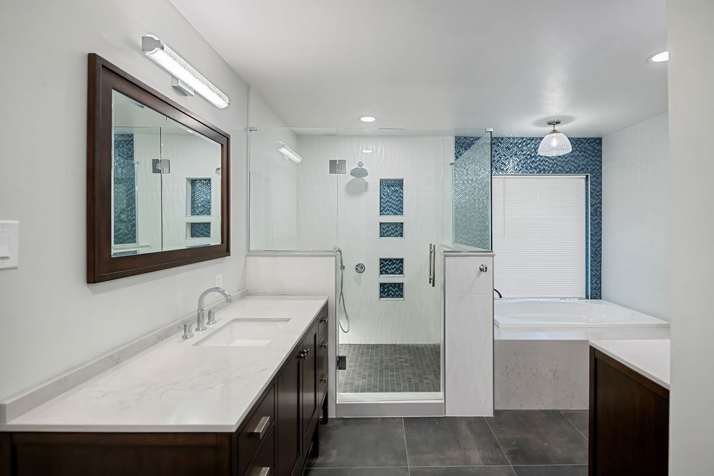 A bathroom remodel with two sinks , a tub and a mirror.