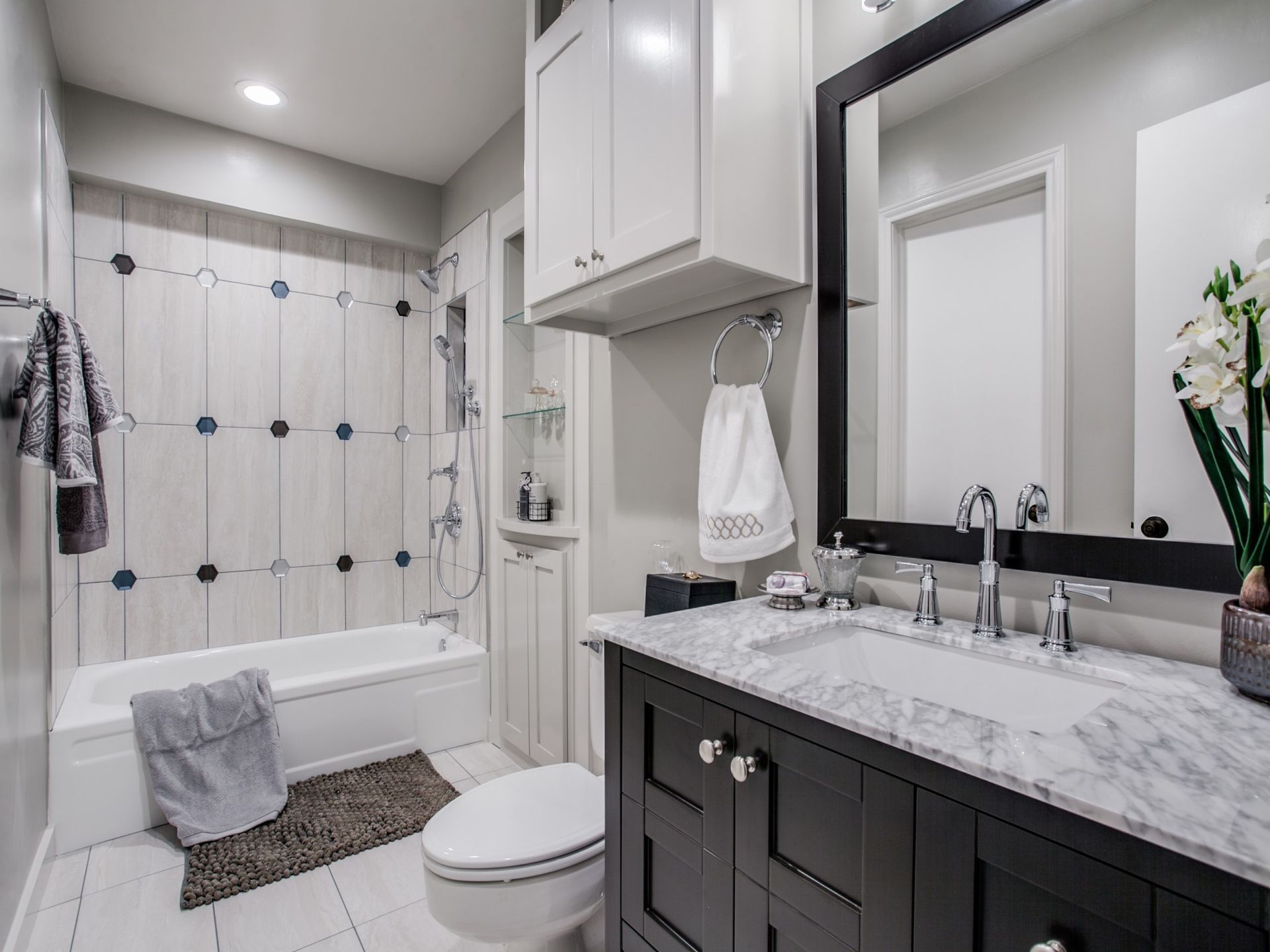 A bathroom with a toilet , sink , tub and mirror.