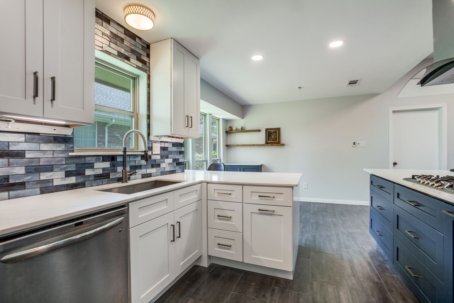 A kitchen with white cabinets , blue cabinets , stainless steel appliances and a large island.