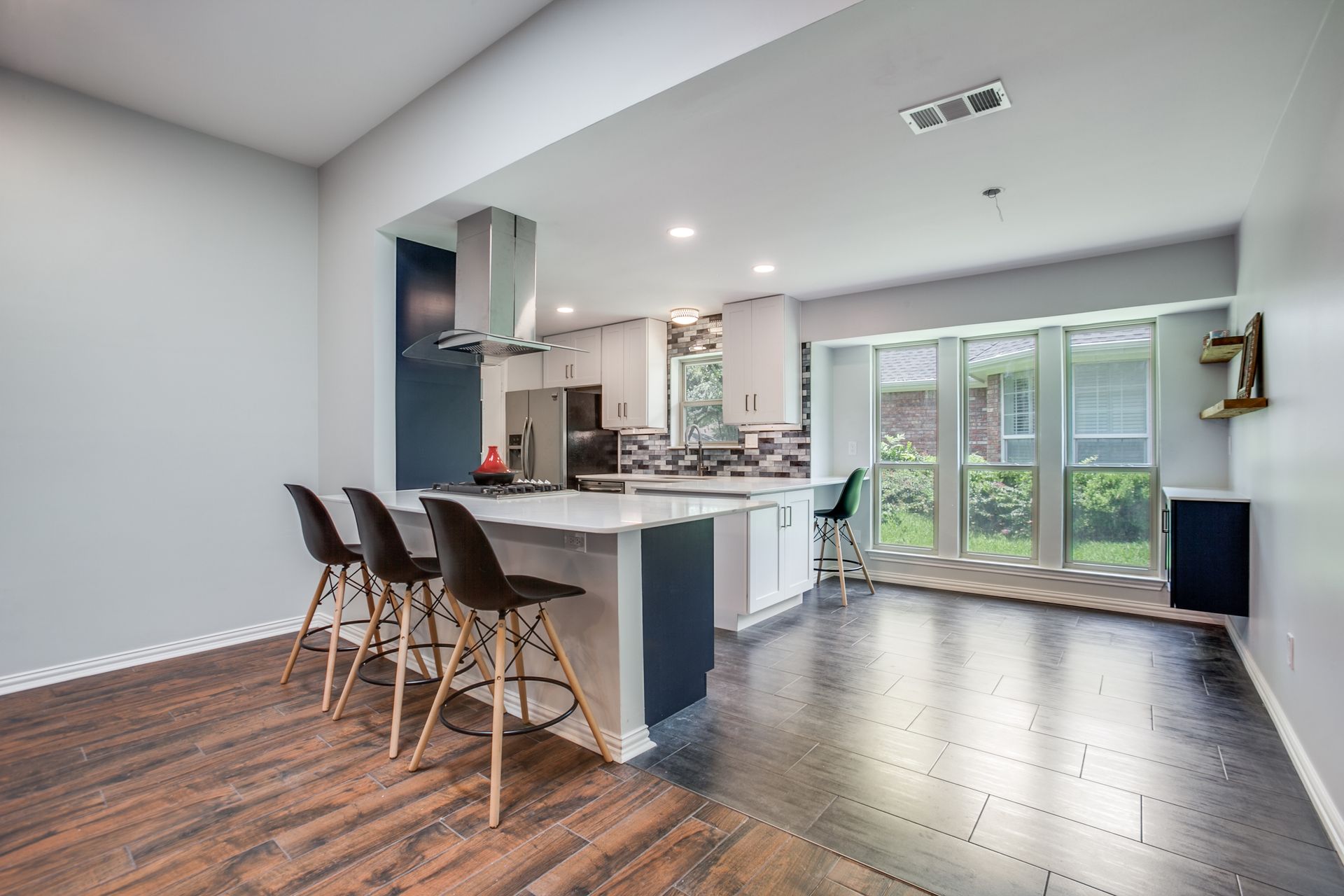 A kitchen with a large island and stools in a living room.