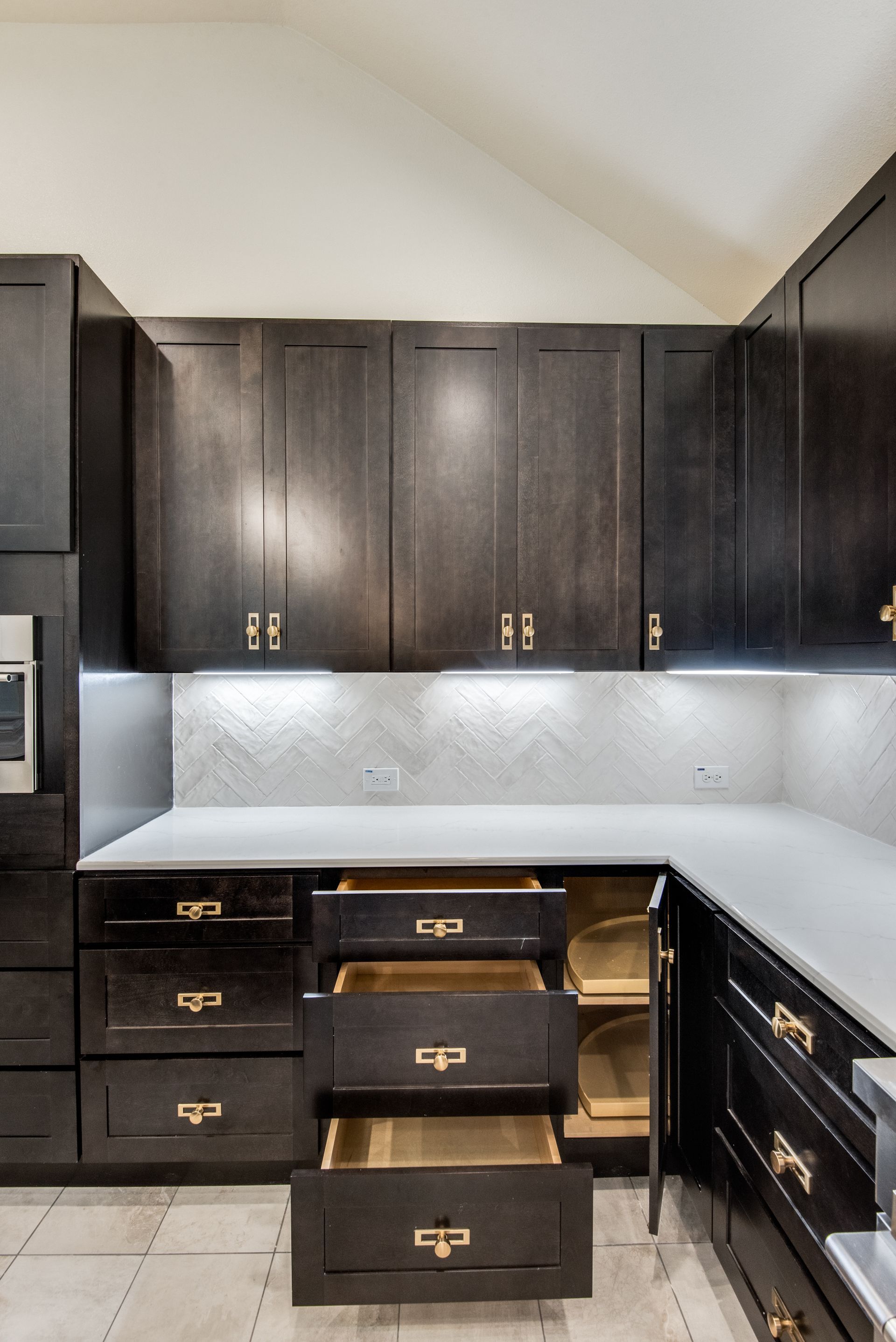 A kitchen with black cabinets and drawers open.