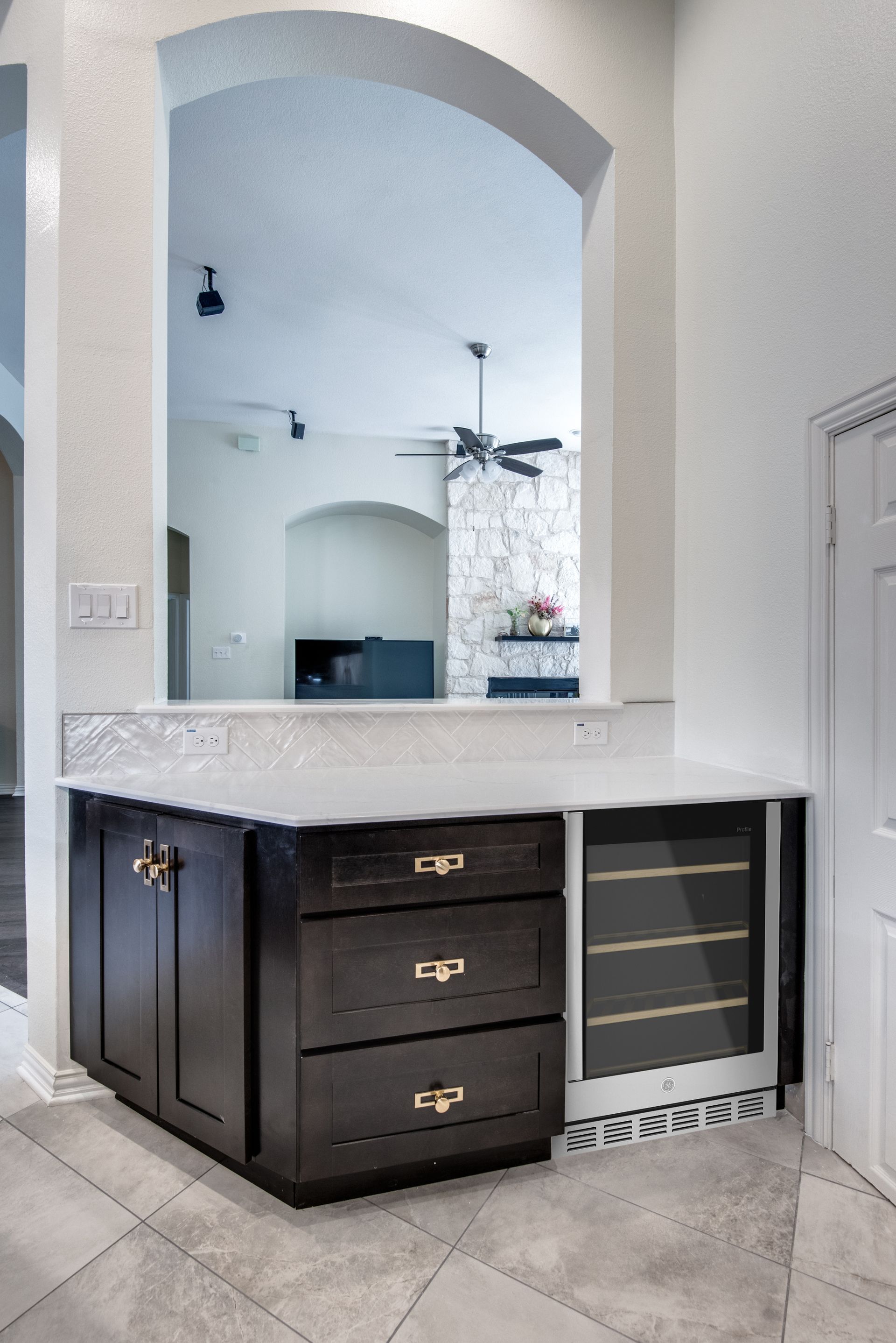 A kitchen with black cabinets and a wine cooler.