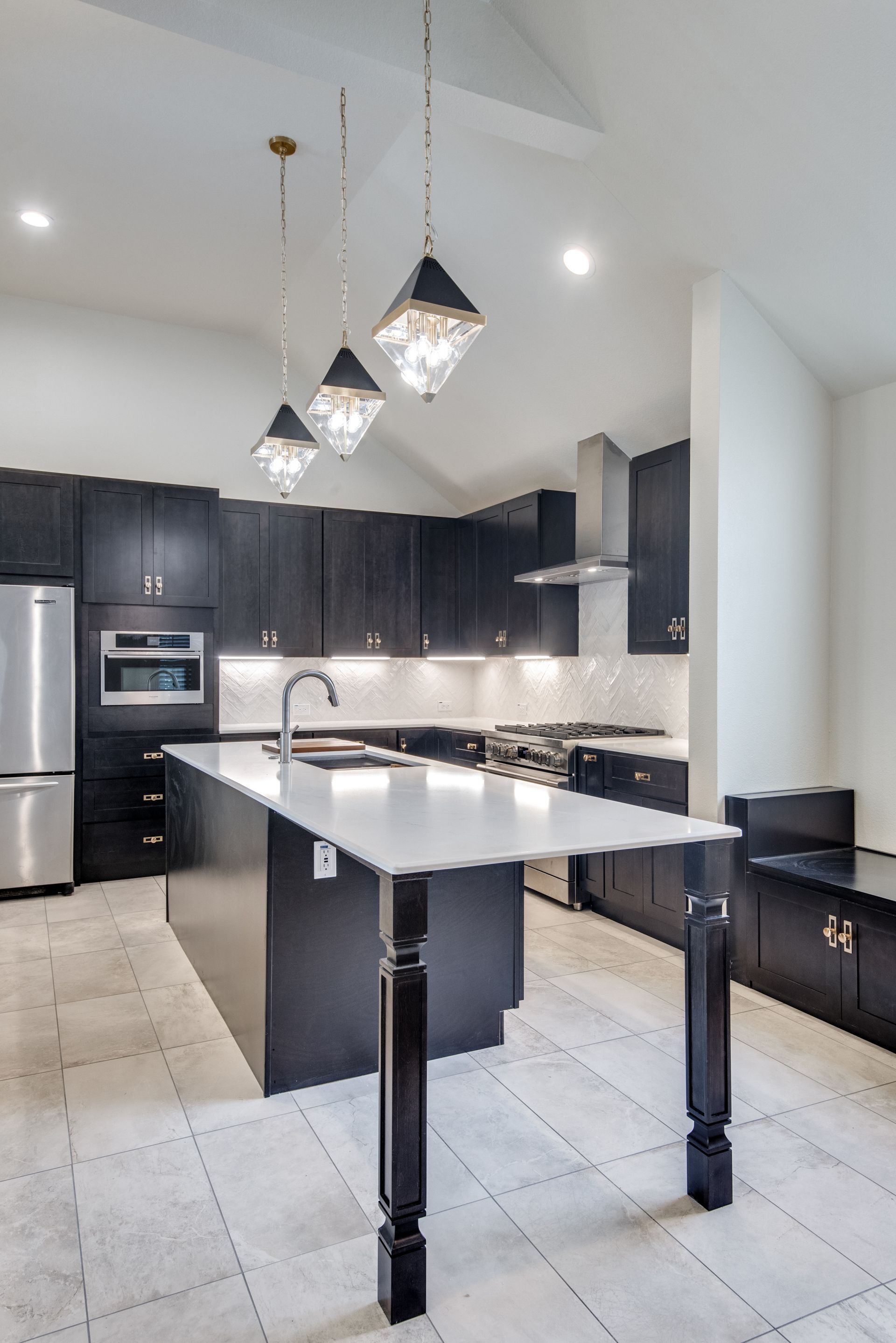 A kitchen with black cabinets and stainless steel appliances and a large island.