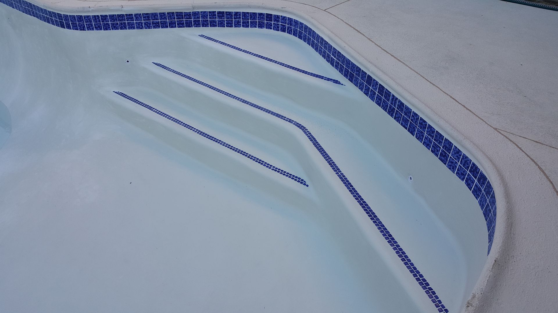 A swimming pool with blue and white tiles and stairs
