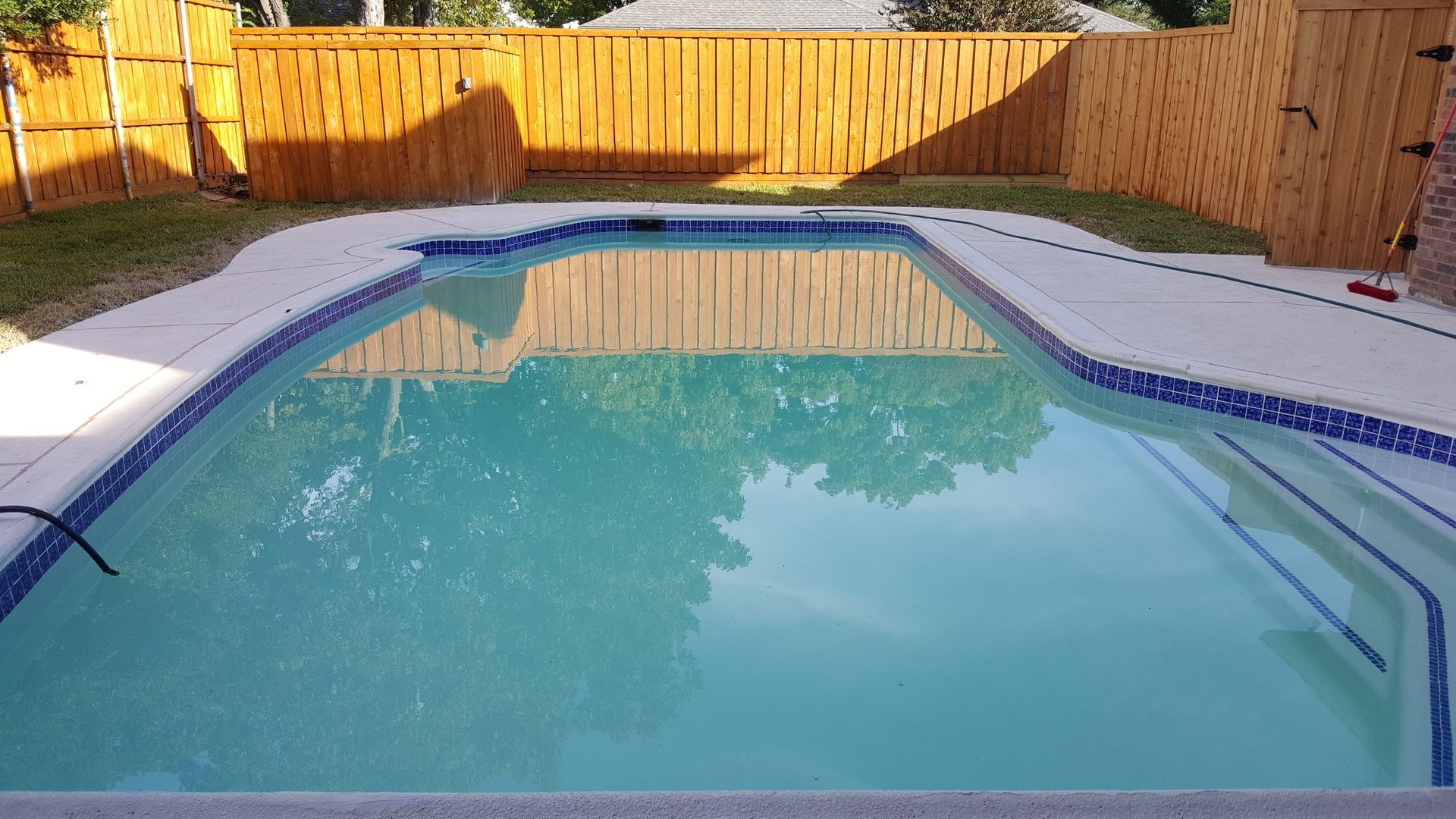 A large swimming pool with a wooden fence surrounding it.