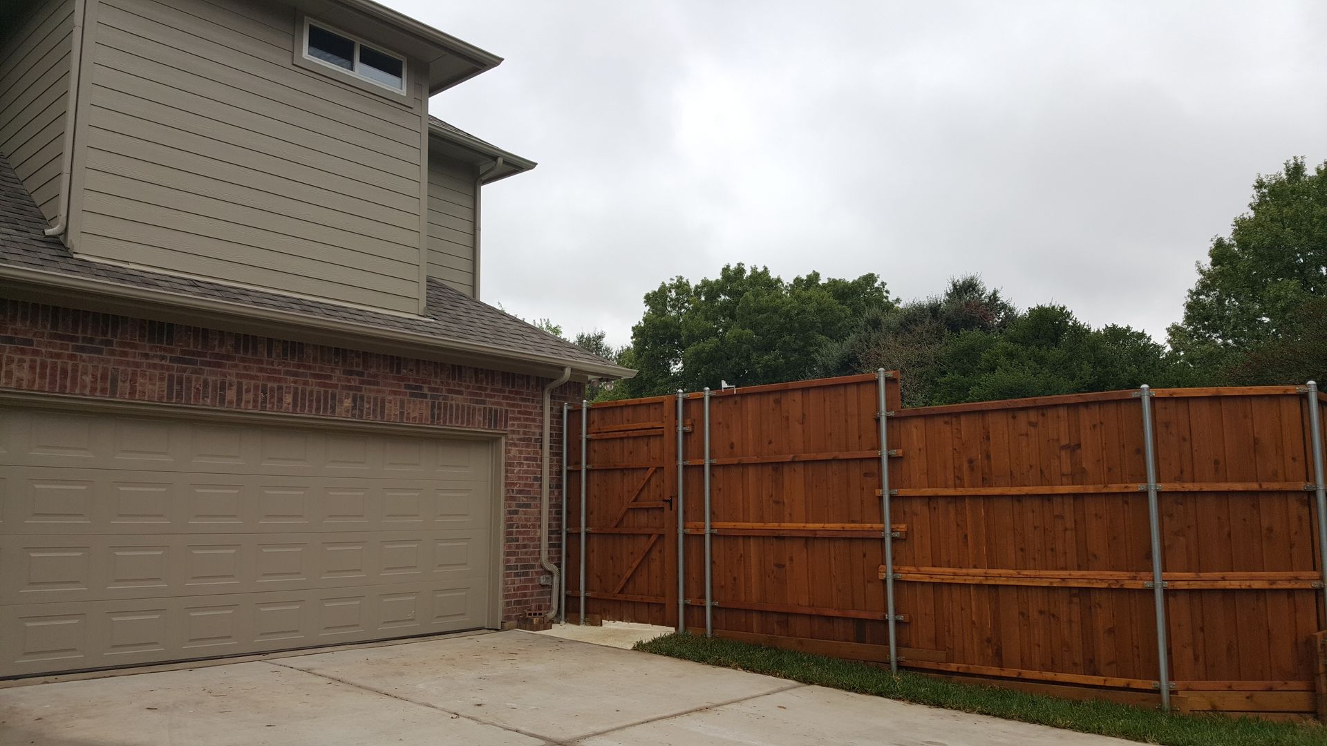 A house remodel with a garage and a wooden fence in front of it.