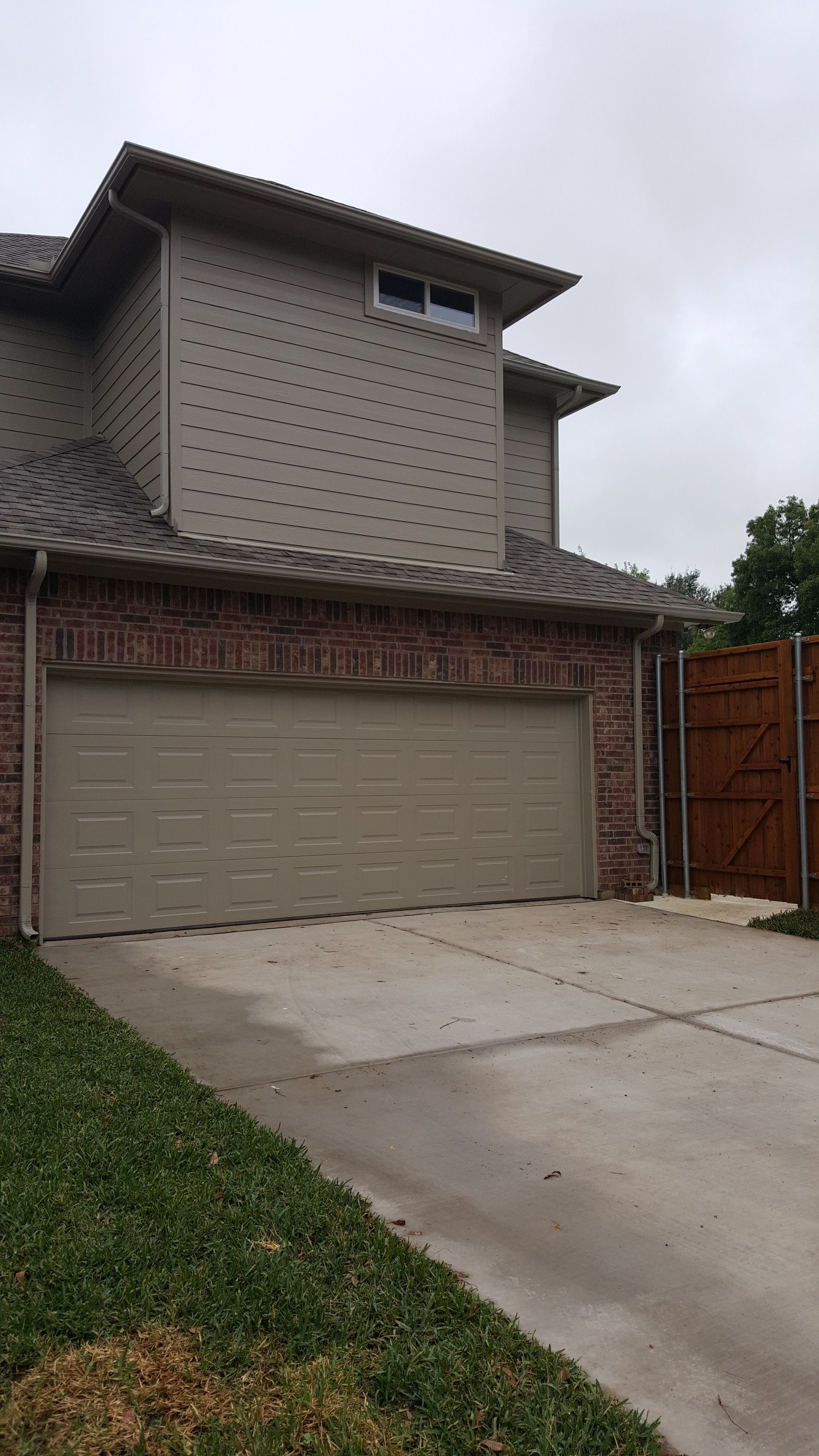 A house remodel with a garage door and a driveway in front of it.