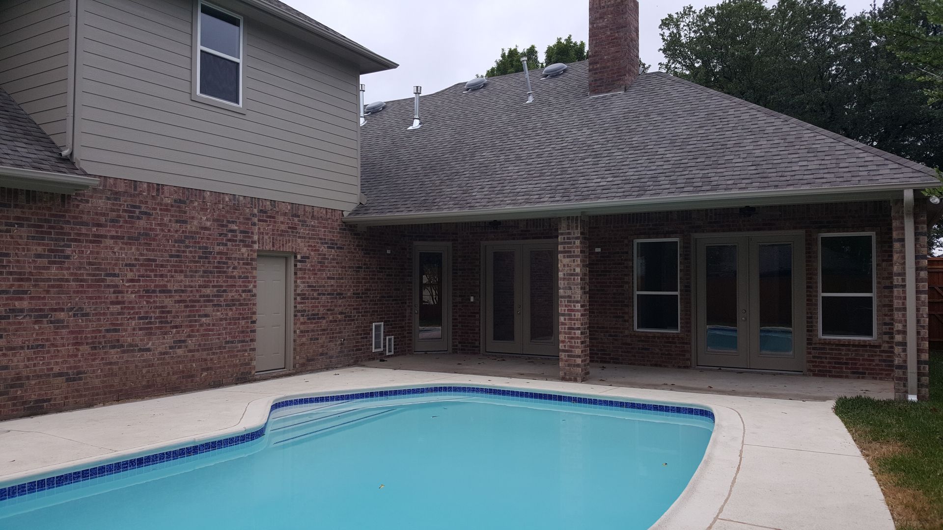 A large house remodel with a swimming pool in front of it