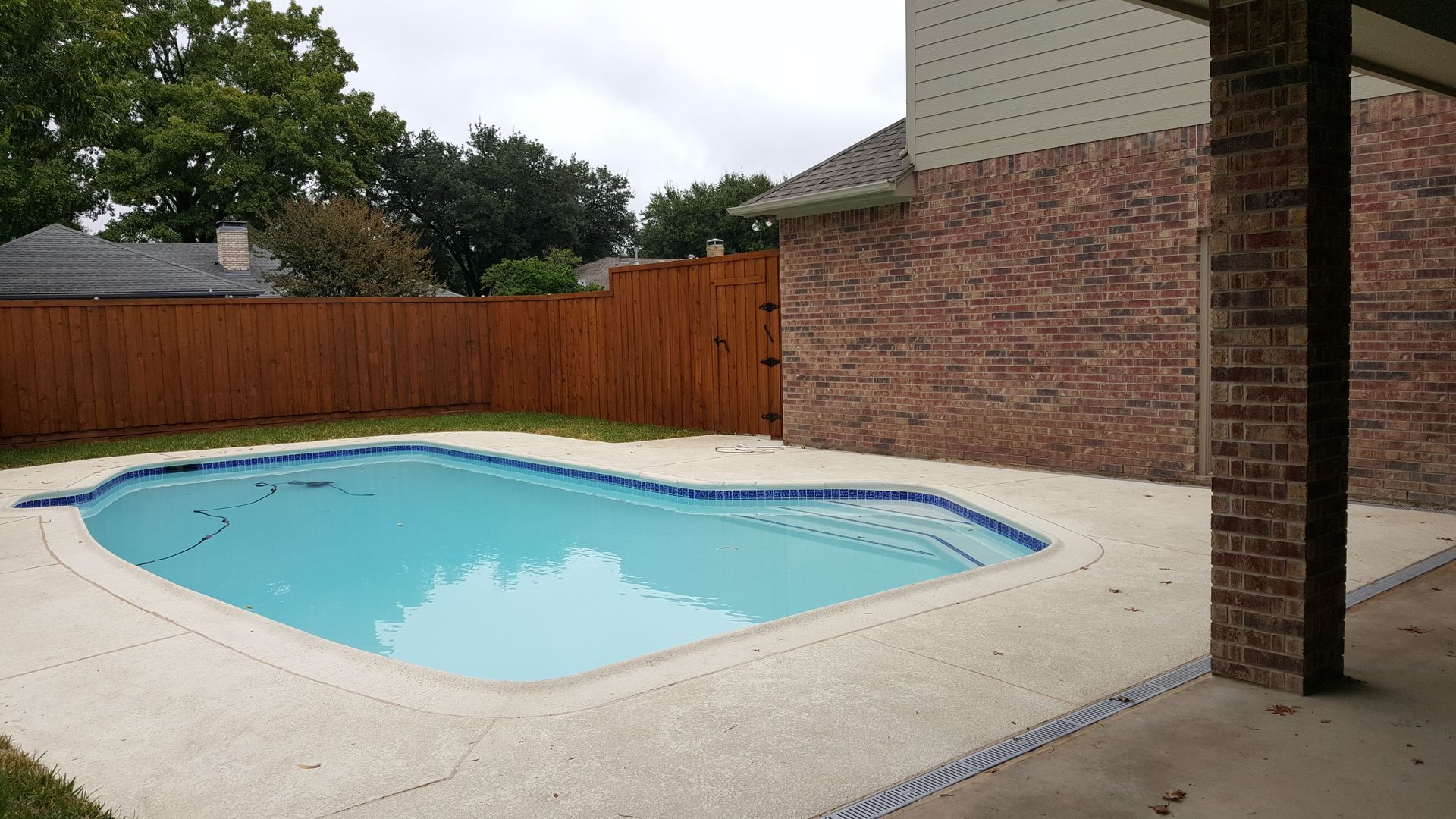 There is a large swimming pool in the backyard of a house remodel.