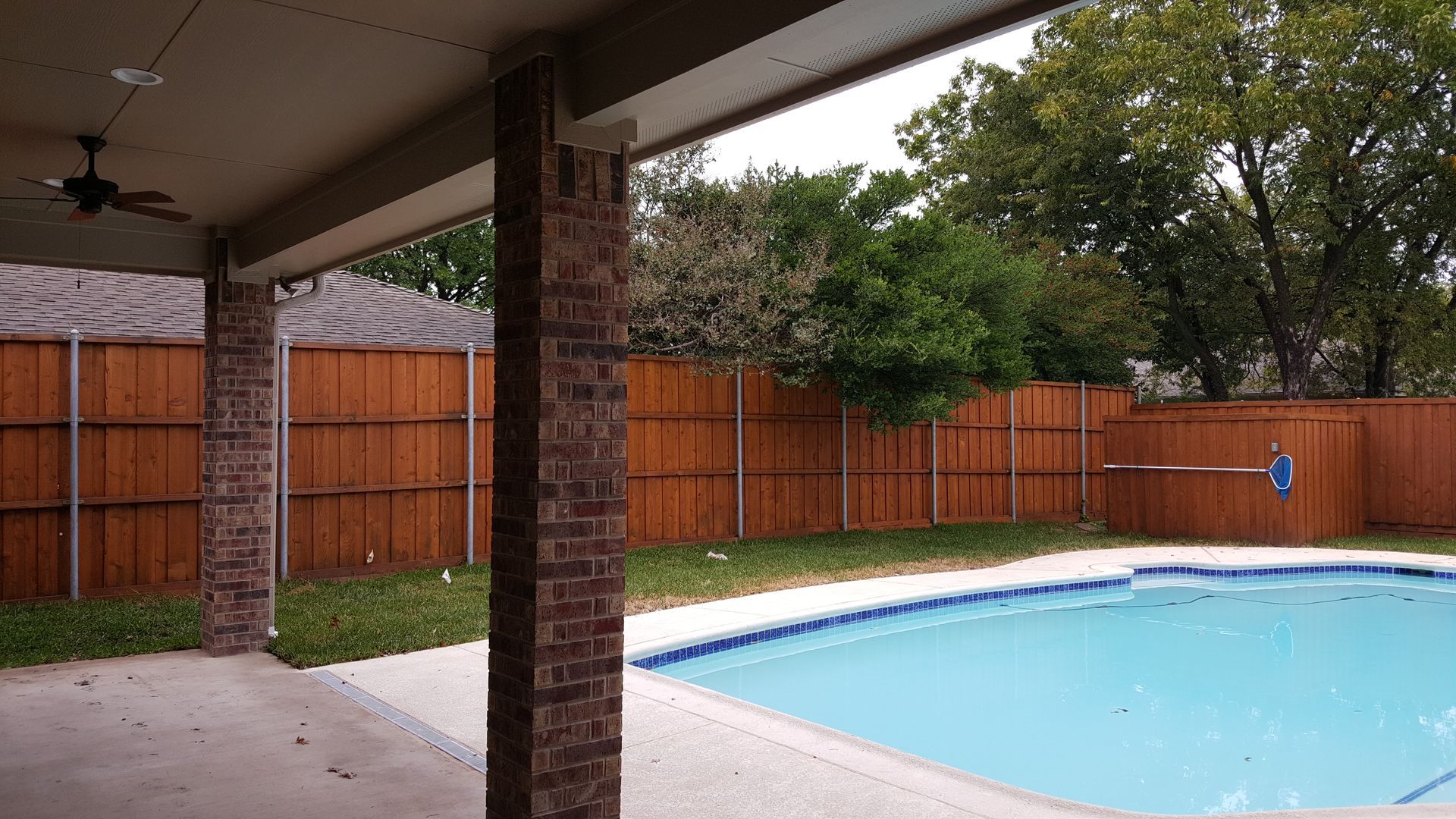A large swimming pool with a wooden fence surrounding it