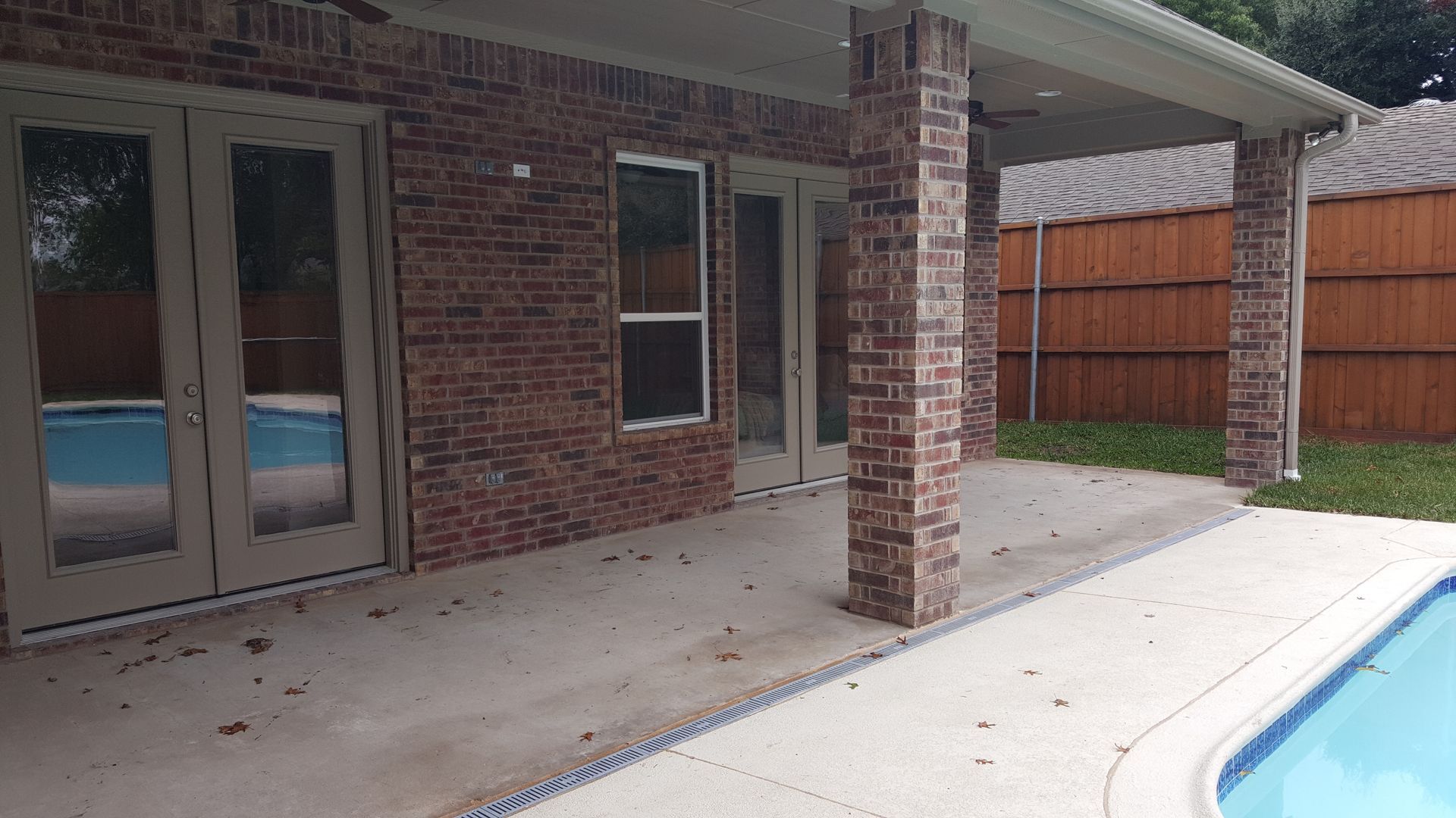 There is a swimming pool in the backyard of a house remodel.