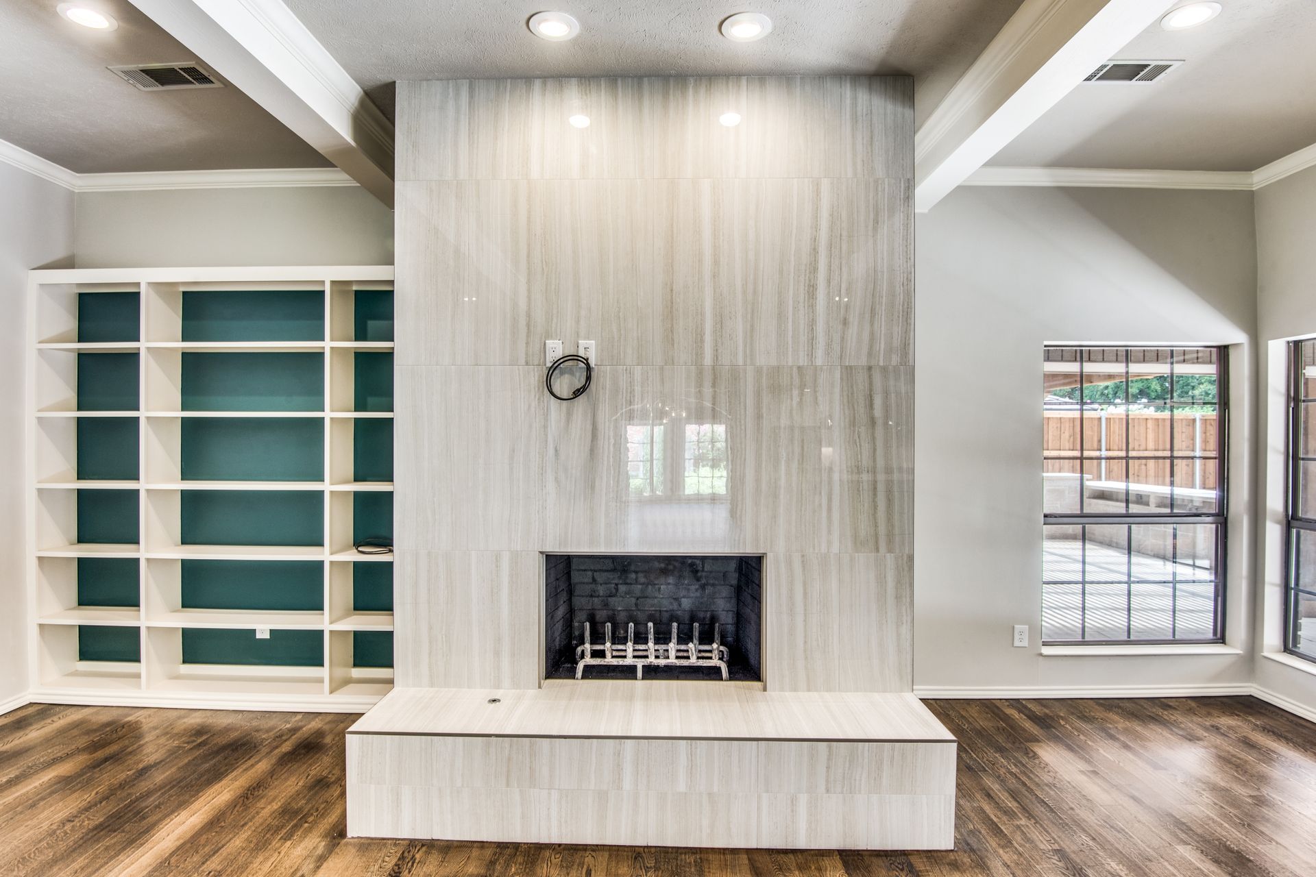 An empty living room with a fireplace and shelves