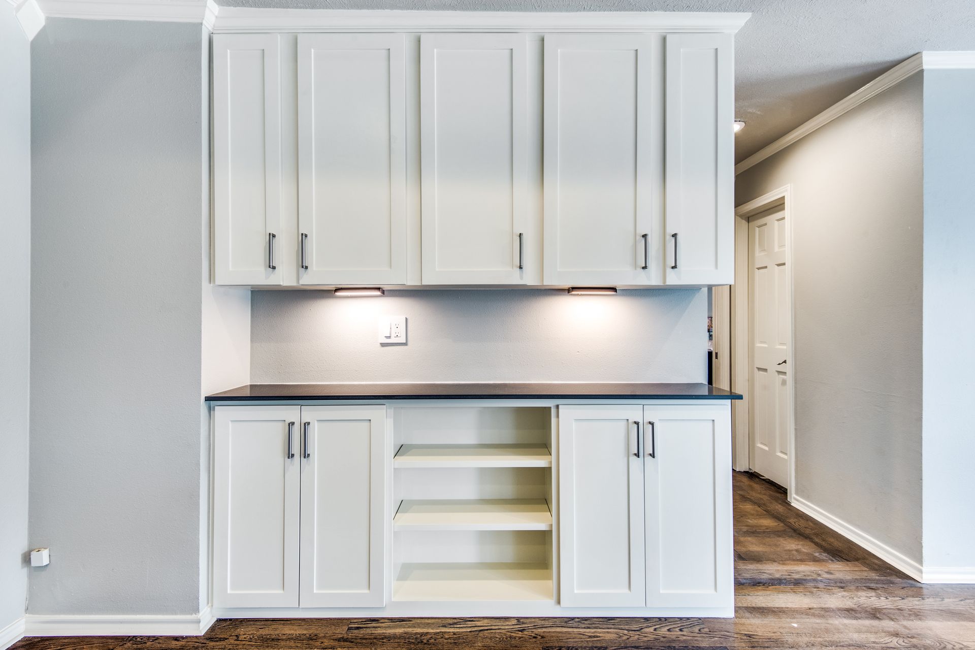 A kitchen with white cabinets and a black counter top.