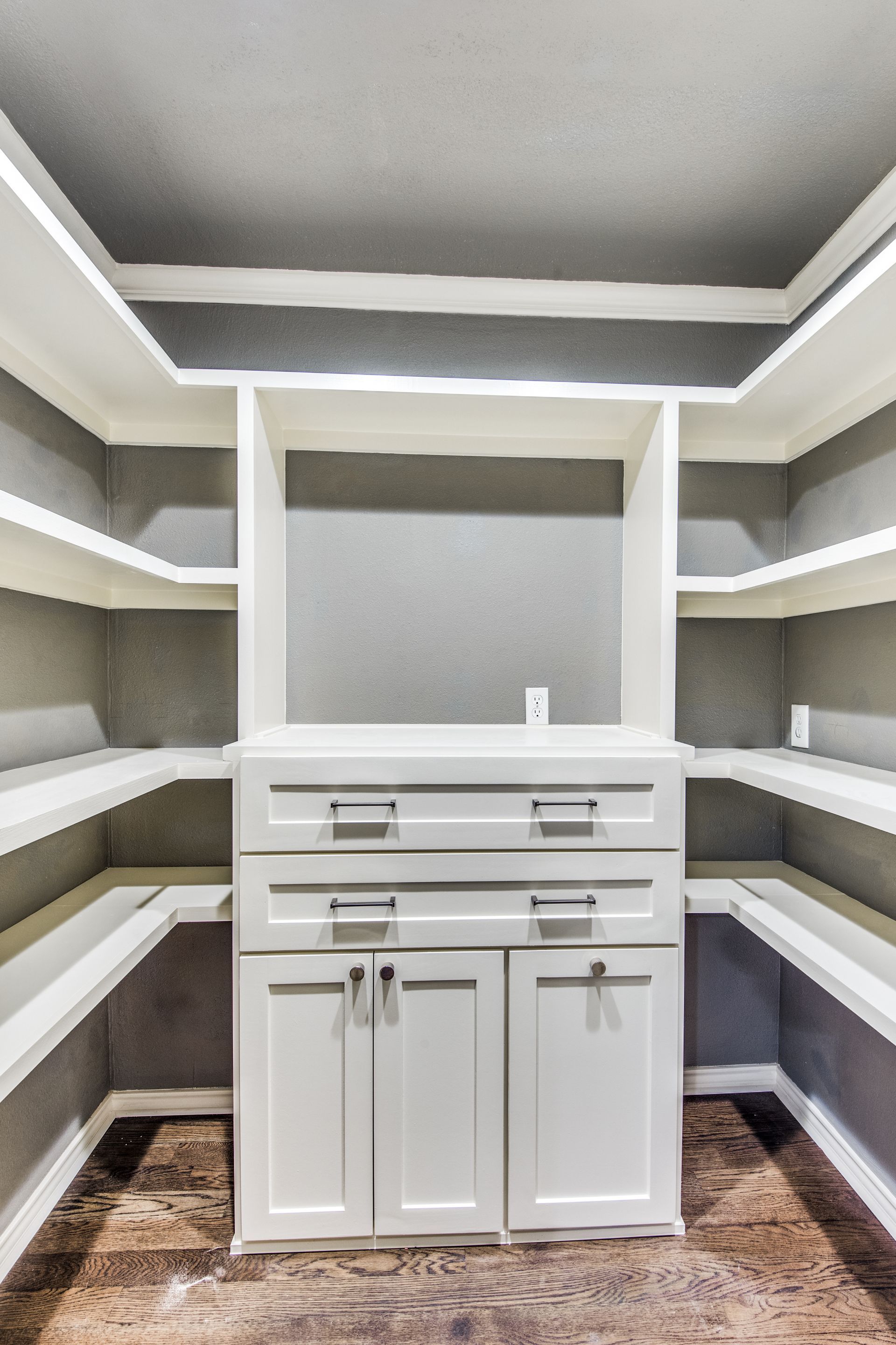 A walk in closet with white cabinets and shelves.