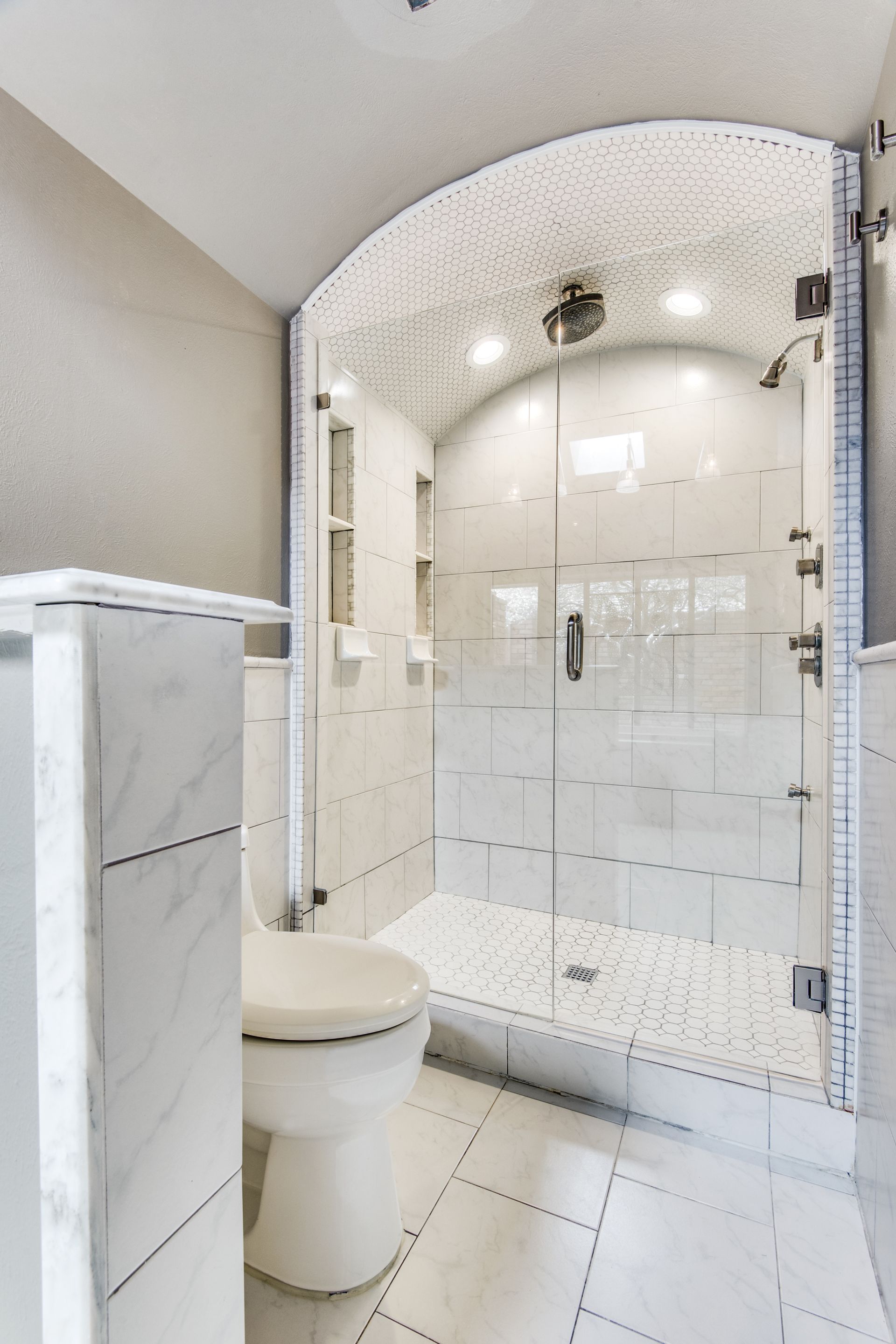 A bathroom remodel with a toilet and a walk in shower.