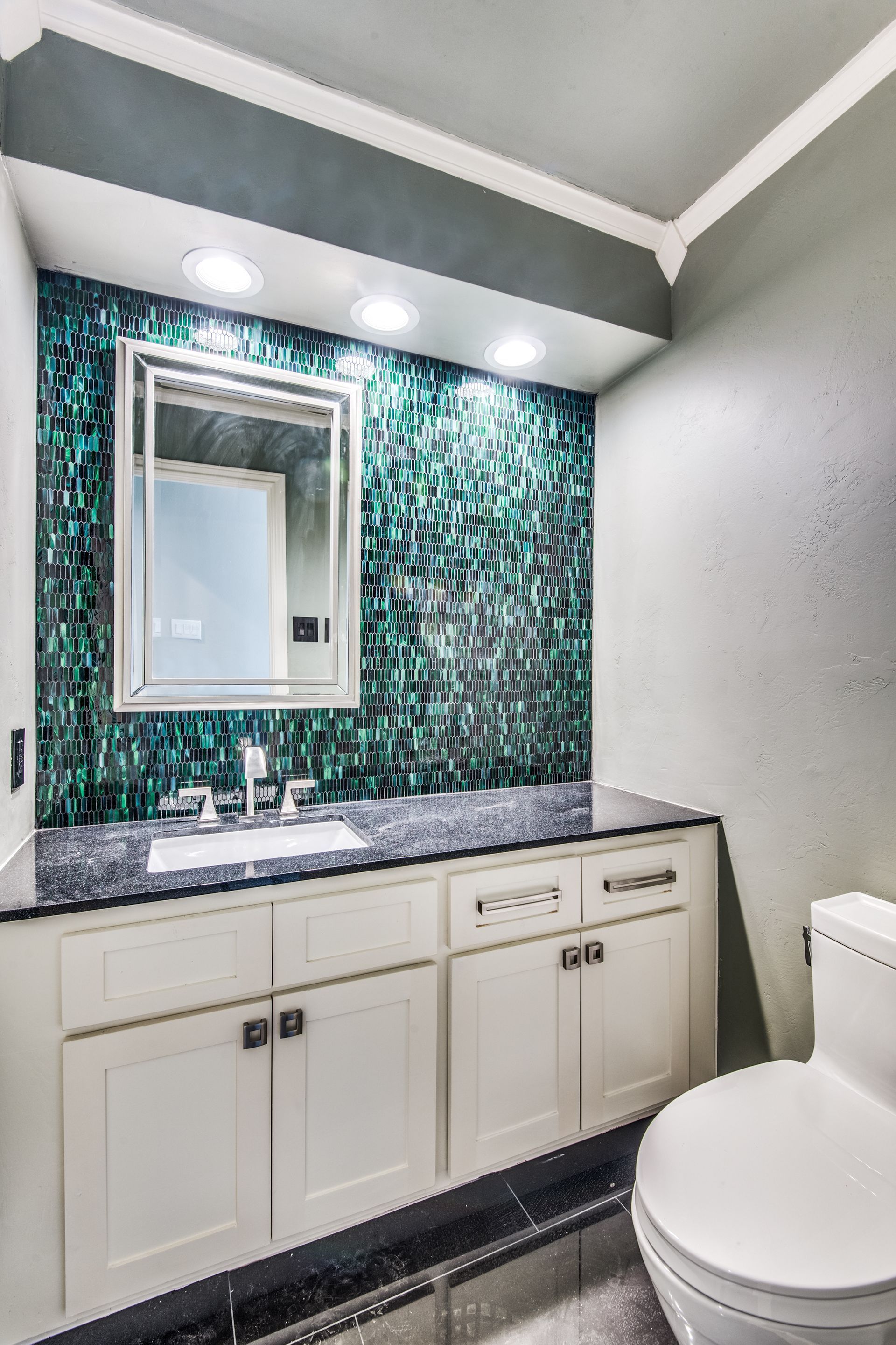 A bathroom remodel with a sink , toilet and mirror.