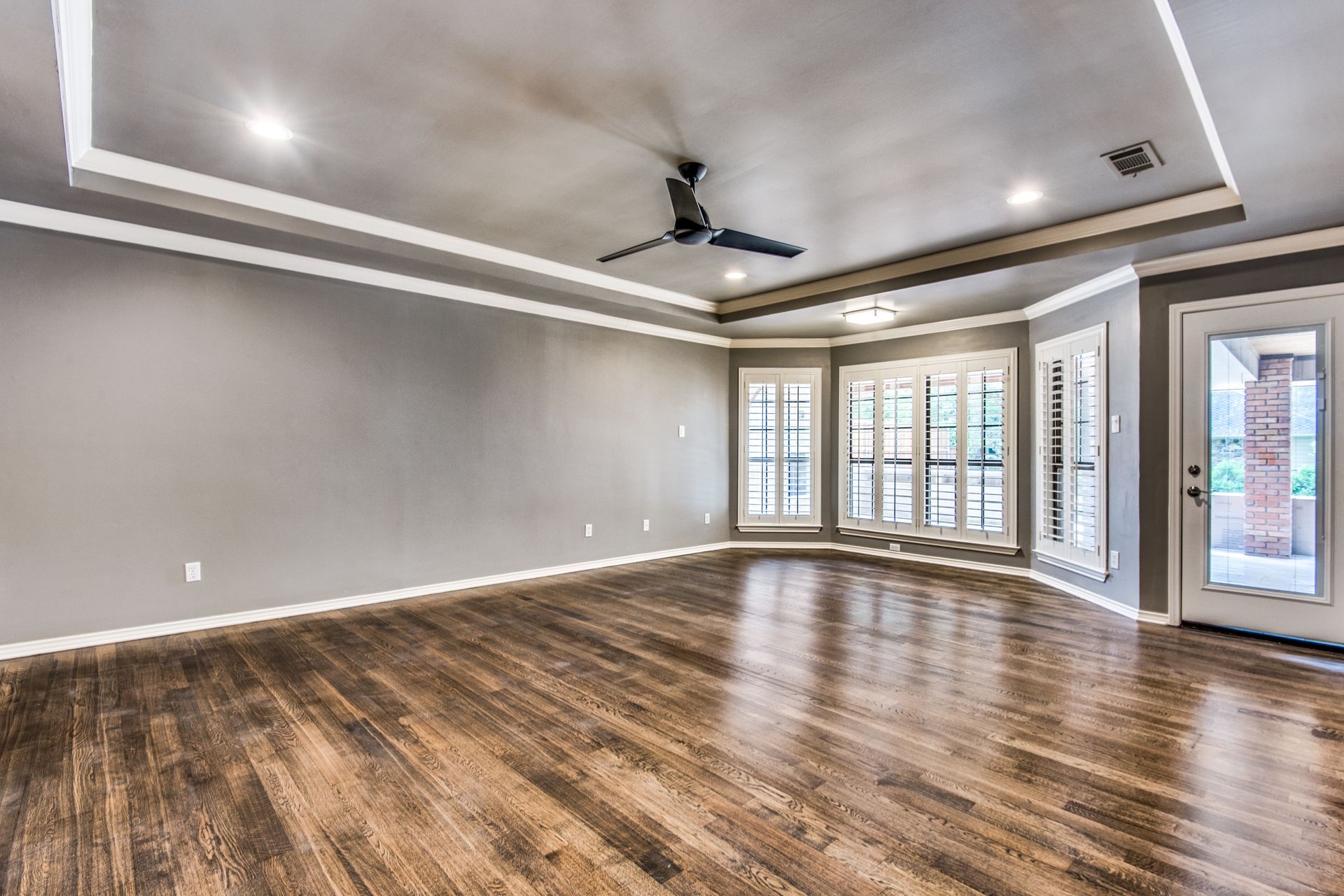 An empty living room with hardwood floors and a ceiling fan.
